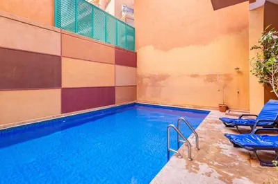 a swimming pool with blue chairs next to a building at Marguerite de Guéliz Piscine & Parking in Marrakech