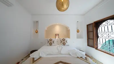 a bedroom with a bed with white sheets and a window at Riad 2 Ksour Marrakesh in Marrakech
