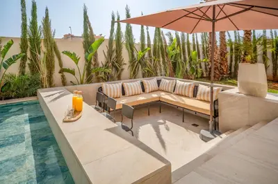 a patio with a couch and an umbrella next to a pool at Villa Bahia Luxury-Pool Breakfast & Golf Access in Marrakech