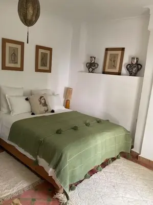 a bedroom with a bed with a green blanket at Riad zouine dans un quartier traditionnel in Marrakech