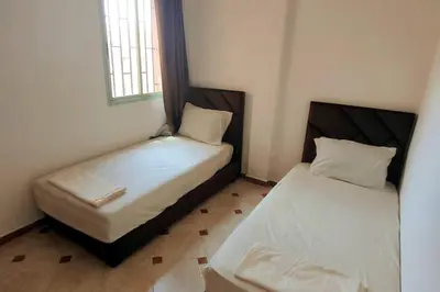 two beds in a small room with a window at Appartement familial in Marrakech