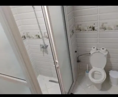a white bathroom with a shower and a toilet at Appartement DUPLEX in Marrakech