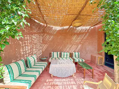 a patio with couches and a table and chairs at Évasion Douce avec jardin, terrasse et piscine privée in El Aggada
