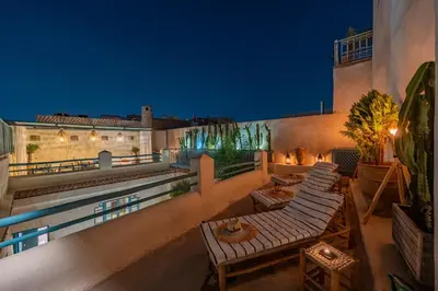 an outdoor patio with tables and chairs at night at Riad Dar Palma Heated Pool Jacuzzi Heart Of Marrakech Medina in Marrakech