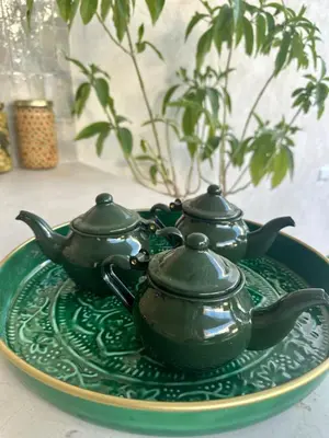 a green plate with three tea pots on it at Riad Daba Chic in Marrakech