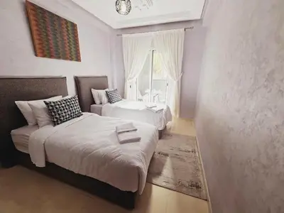a bedroom with two beds and a couch and a window at Luxurious and charming apartment in Marrakech