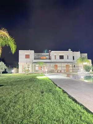 a large white building at night with a green yard at Villa privée in Marrakech