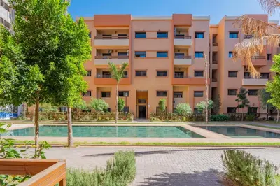 an apartment with a swimming pool in front of a building at Appartement au coeur de Marrakech à côté de la gare avec piscine in Marrakech