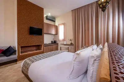 a hotel room with a white bed and a fireplace at Al destino Resort Marrakech in Marrakech