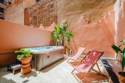 a patio with a hot tub and chairs and plants at Duplex Style and Confortable au Centre de la Ville in Marrakech