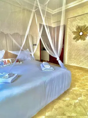 a bed with white drapes in a bedroom at Marakech home in Marrakech