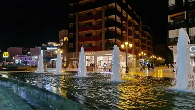 a fountain in the middle of a city at night at APPART GUELIZ PLAZA MARRAKECh in Marrakech