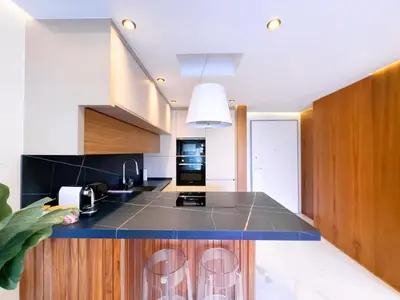 a kitchen with a black counter top and wooden cabinets at Appt de Luxe avec Terrasse,PiscinePartagée & wifi in Marrakech