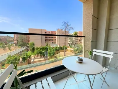 a balcony with a white table and chairs and a large window at Appt de Luxe avec Terrasse,PiscinePartagée & wifi in Marrakech