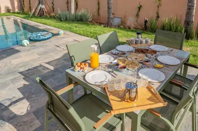 a table with plates of food on it next to a pool at Sumptuous Villa, Heated Pool, 15minutes to City Center, Daily Housekeeping, Private Cook and Chauffeur, Games in Marrakech