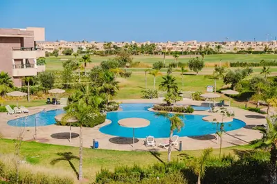an aerial view of a resort pool with palm trees and umbrellas at 3 Bedroom Apartment with Pool View Prestigia in Marrakech