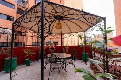 a patio with a table and chairs under an umbrella at Gueliz family Express in Marrakech