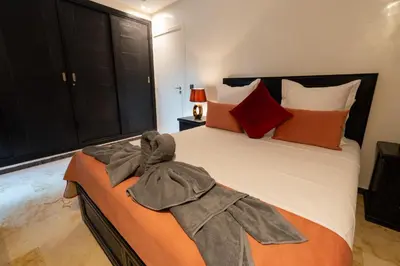 a bedroom with a bed with white sheets and red pillows at Gueliz family Express in Marrakech