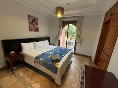 a bedroom with a bed with a blue blanket at Appartement standing piscine la palmeraie in Marrakech