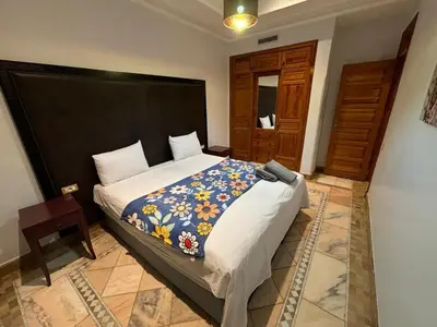 a bedroom with a large bed with a large headboard at Appartement standing piscine la palmeraie in Marrakech