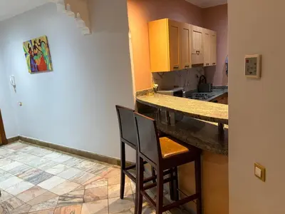 a kitchen with a counter and two chairs in a room at Appartement standing piscine la palmeraie in Marrakech