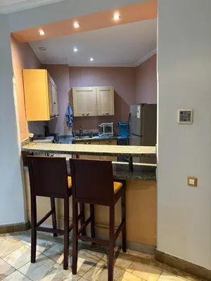 a kitchen with two chairs and a counter with a counter top at Appartement standing piscine la palmeraie in Marrakech