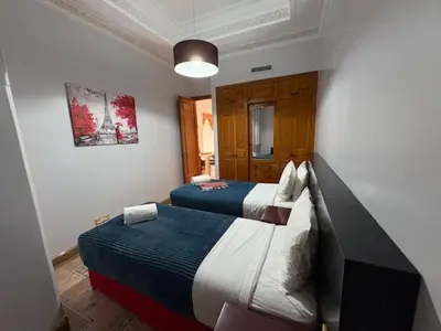 a bedroom with two beds and a painting on the wall at Appartement standing piscine la palmeraie in Marrakech