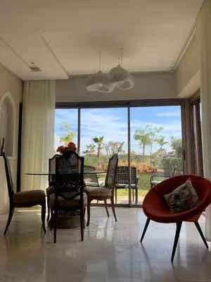 a living room with a table and chairs and a large window at Mon paradis Golf & Piscine in Marrakech