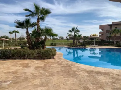 a swimming pool with palm trees and a building at Mon paradis Golf & Piscine in Marrakech