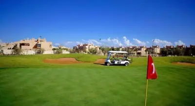 a golf cart on a green with a red flag at Mon paradis Golf & Piscine in Marrakech