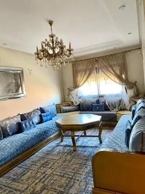 a living room with a blue couch and a table at Magnifique F3 au Riad Arfoud avec piscine in Marrakech