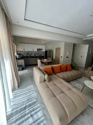 a living room with a large couch with orange pillows at Appartement spacieux 1 chambre avec piscine Palmeraie Gates in Marrakech