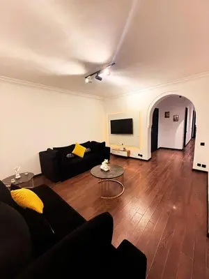 a living room with a black couch and a tv at Beautiful apartment in a very good location and free parking in Marrakech