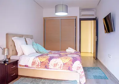 a bedroom with a bed with a flowered comforter at Appartement Chic et Lumineux, Proche Gare in Marrakech