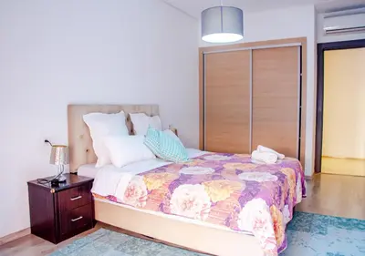 a bedroom with a bed and a night stand with a lamp at Appartement Chic et Lumineux, Proche Gare in Marrakech