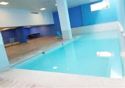 a large swimming pool in a room with a table at Appartement Chic et Lumineux, Proche Gare in Marrakech