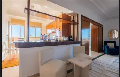 a kitchen and living room with a counter and a table at Lux apartment With a Sunset View in Marrakech