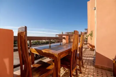 a wooden table and chairs on a balcony with the ocean at Lux apartment With a Sunset View in Marrakech