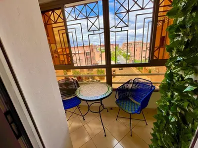 a balcony with a table and chairs and a window at Beautiful family apartment with parking in Marrakech