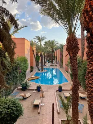 a swimming pool with chairs and palm trees in a resort at Riad& 4 Chambres Avec La piscine in Marrakech