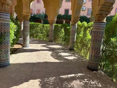 a courtyard of a building with columns and plants at Riad& 4 Chambres Avec La piscine in Marrakech
