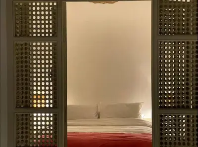 a bedroom with a bed with atained window with a red blanket at Riad privé Dar Sun 2 bassins & Rooftop coeur medina in Marrakech