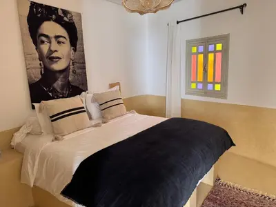 a bedroom with a bed with a portrait of a man at Riad privé Dar Sun 2 bassins & Rooftop coeur medina in Marrakech