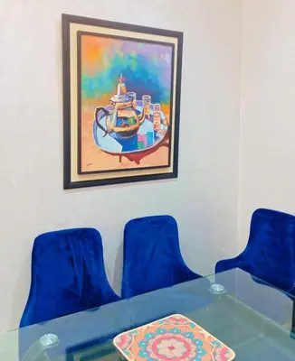 a table with blue chairs and a painting on the wall at Cozy Apartment Marrakech Airport in Marrakech