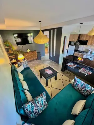 a living room with a green couch with pillows at Appartement avec piscine privée in Marrakech