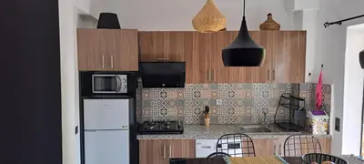 a kitchen with wooden cabinets and a white refrigerator at Appartement avec piscine privée in Marrakech