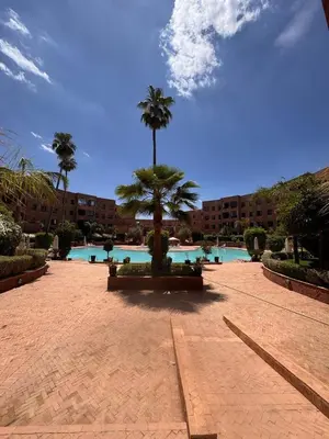 a courtyard with a palm tree and a swimming pool at Superbe appartement Marrakech Piscine Wifi Climatisation in Marrakech