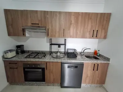 a kitchen with wooden cabinets and a stainless steel dishwasher at Appartement a hivernage in Marrakech