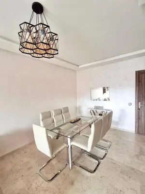 a dining room with a glass table and white chairs at Appartement a hivernage in Marrakech
