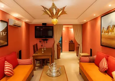 a living room with orange walls and a dining room at Appart AMITAF in Marrakech